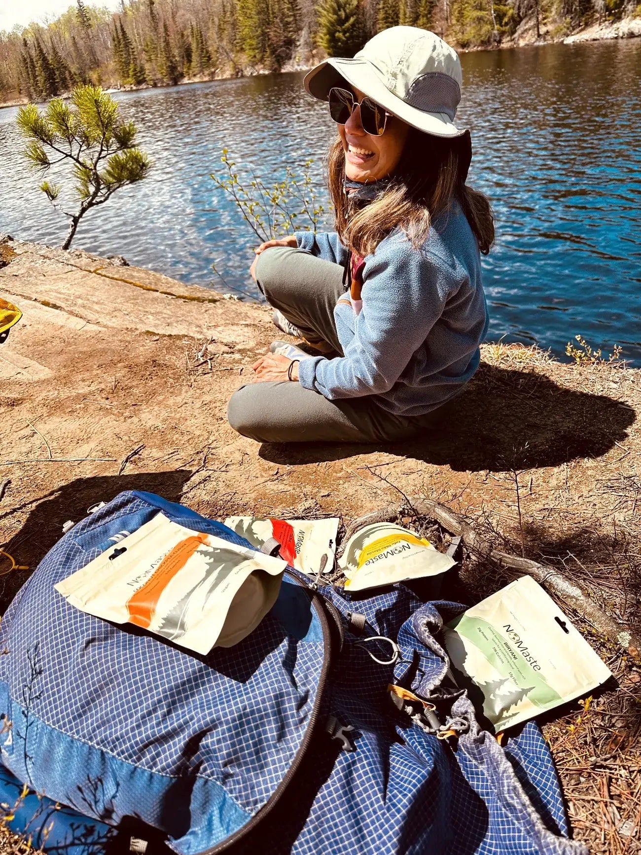 Neha, founder of NOMaste, beside a lake with NOMaste meals
